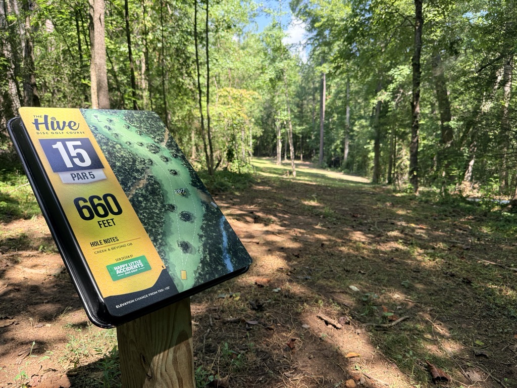 The Hive Hole 15 tee sign beside the wooded fairway